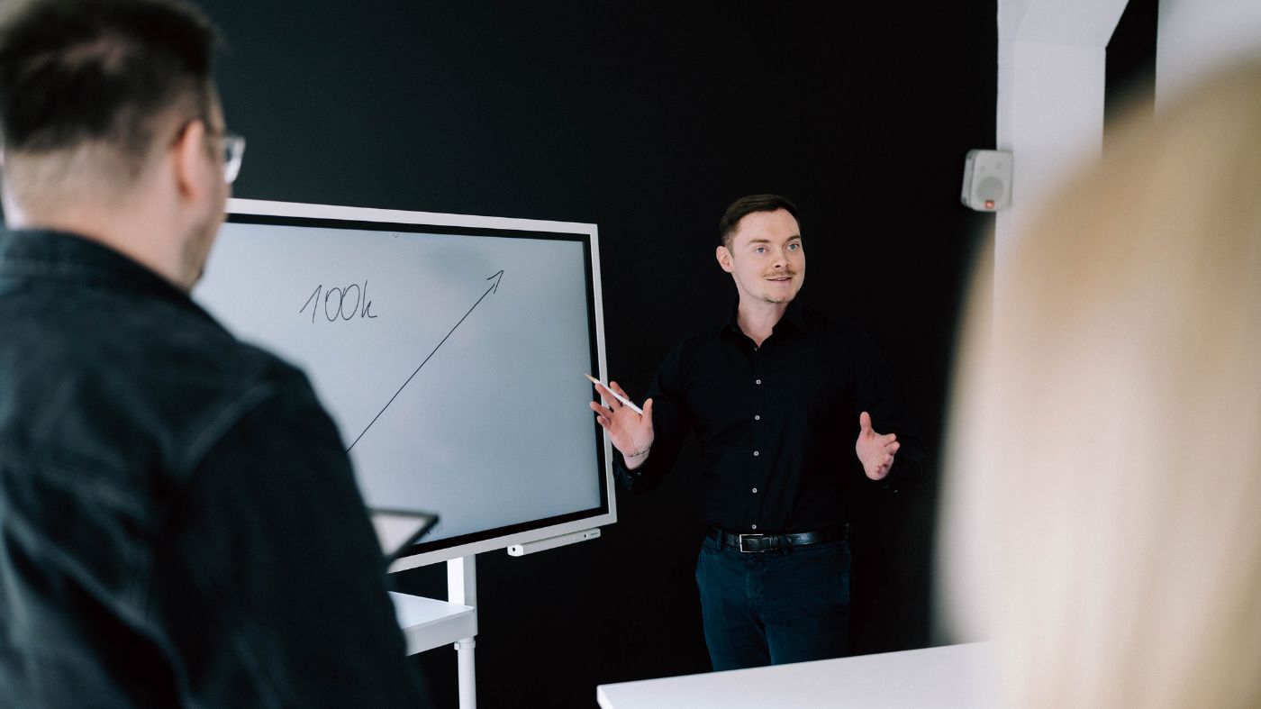 Schulungen für Magento und Shopware Ein Mann präsentiert eine Grafik an einem Whiteboard.